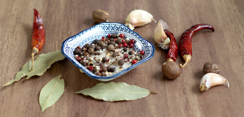 Sea salt and spices in small blue plate, chilli, Bay leaf, close-up, on wooden background
