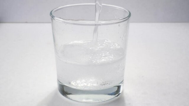 Clear fizzy soda or seltzer being poured into clear glass