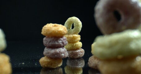 Three pyramids of multicolored Cereal Hoops. Cereal Hoops crumbs on the table. Honey hoops. Food and drink background.