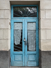 Vintage glass door with blue paint chip and old curtains