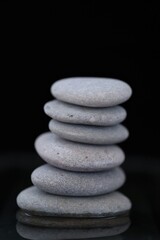 Zen Stones.spa stones set in water on black background. Harmony, balance and balance concept. Beauty and health .Gray stones column on black background