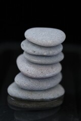 Zen Stones.spa stones set in water on black background. Harmony, balance and balance. Beauty and health.Gray stones column on black background
