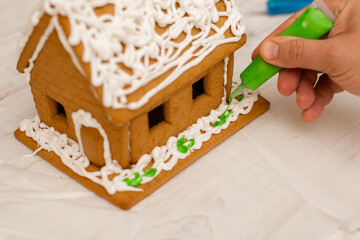 The boy makes a gingerbread house. Preparing for the holiday, creative activity.