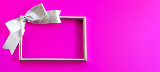 Silver empty frame with a bow on a fuchsia background. Banner. Greeting card for New Year, Christmas, Thanksgiving, mother's Day, Birthday. A place for a creative concept.