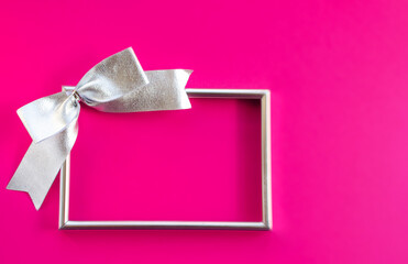 Bright holiday background. Empty frame and bow on pink background. Concept greetings for Christmas, thanksgiving, New year, mother's Day, birthday, Valentine's Day. Flat lay, copy space