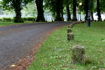 The narrow road in Scottish village with a stone bollard at sides with trees in background