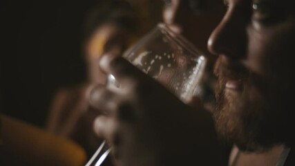 Close up of bearded man drinking beer in night club