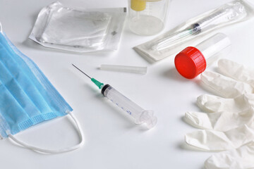close on a a syringe with needle among pharmacy equipment and a face mask