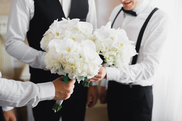 Beautiful man, groom holding big and beautiful wedding bouquet with flowers