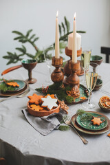 Festive Christmas and New Year table setting in scandinavian style with rustic handmade details in natural and white tones. Dining place decorated with pine cones, branches and candles