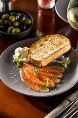 Delicious homemade smoked salmon slices with toasted bread and cream cheese on wooden table at restaurant