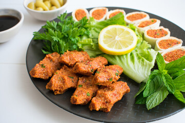Turkish raw meatballs(cig kofte). Top view of Turkish meatballs cut into lettuce, tomato, pickle and lemon, pomegranate syrup and sushi