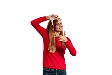Obraz na płótnie Canvas Beautiful young woman in a red sweater, making the gesture of photographing with her hands, isolated on a white background.
