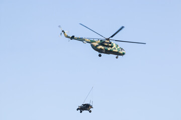 A military helicopter painted in camouflage color is flying high in the sky. Close up. The...