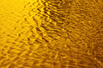 Golden rippling water with sunset reflection texture background. 