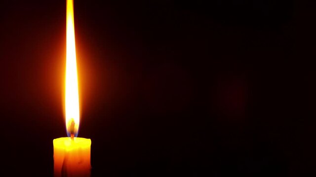 burning candle in the dark with copy space, a symbol of sorrow for the dead . 