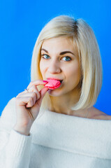 Photo of charming woman in basic clothing eating two macaron biscuits isolated over pink background