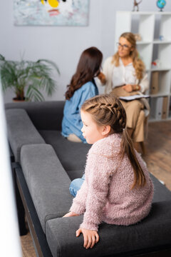 daughter sitting on sofa while mother talking to psychologist, stock image