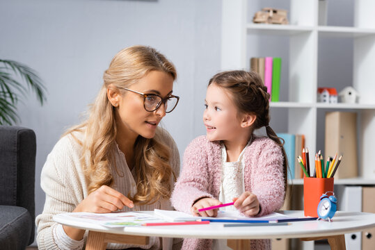  girl drawing pictures with colorful pencils while visiting psychologist