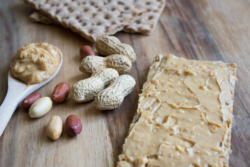 Peanut butter and peanuts on wooden background