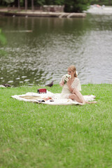 A young girl in a white dress with white flowers in her hands. By the lake on a sunny summer day.