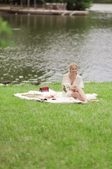 A young girl in a white dress with white flowers in her hands. By the lake on a sunny summer day.