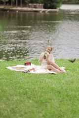 A young girl in a white dress with white flowers in her hands. By the lake on a sunny summer day.