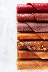 The pastille in the assortment is rolled up in the form of a tube. Healthy dessert on a light background. Various types of dried fruits and berry juices. Natural product without sugar. Top view.