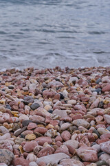 A pebble beach without people with an incoming wave. Transparent clean water.