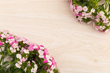 Two bunches of pink flowers in corners on wooden background