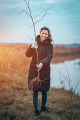 young female planting seedling in park to preserve environment