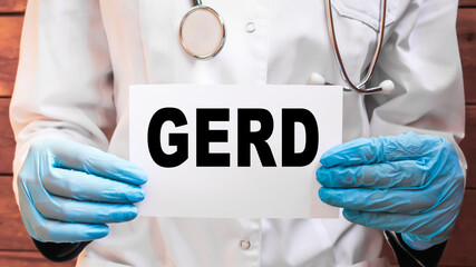 The doctor's blue - gloved hands show the word GERD - . a gloved hand on a white background. Medical concept. the medicine