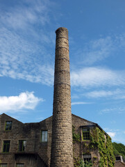 old mill building and tall chimney with blue cloudy sky in hebden bridge west yorkshire