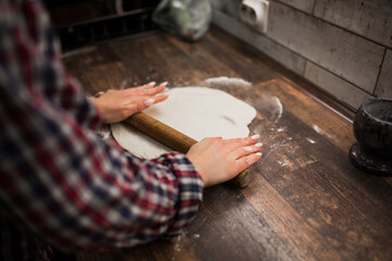 female hands roll out pizza dough