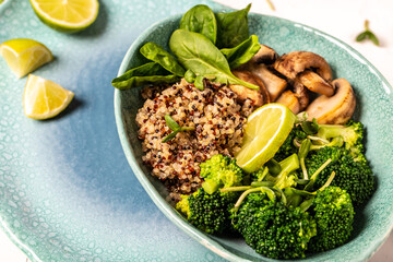 Quinoa salad in bowl with broccoli, mushrooms and spinach on a light background. Quinoa superfood concept. Clean healthy detox eating. Vegan vegetarian food. Top view