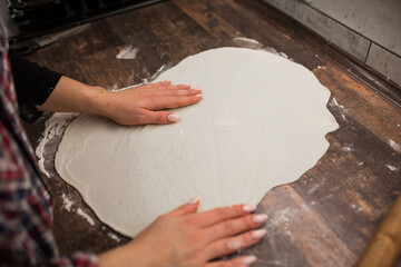 female hands roll out pizza dough