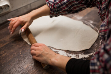 female hands roll out pizza dough
