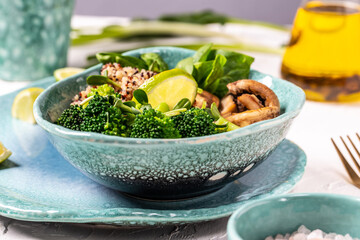 Quinoa salad in bowl with broccoli, mushrooms and spinach on a light background. Quinoa superfood concept. Clean healthy detox eating. Vegan vegetarian food. Top view