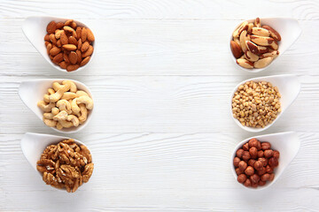 Assorted peeled nuts in a white bowl. Six types of nuts. Natural product. White background. Copy space.