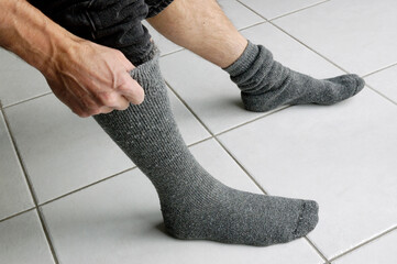 Man pulling up his socks on tile floor