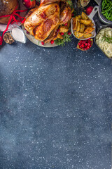 Christmas or New Year turkey dinner. Baked turkey with potato, red berries and sage leaves, on Christmas dinner table with Xmas tree, gift and candles background