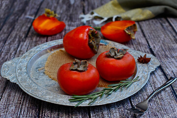 Bright, ripe persimmons on a silver platter. Healthy food concept