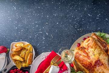 Christmas or New Year turkey dinner. Baked turkey with potato, red berries and sage leaves, on Christmas dinner table with Xmas tree, gift and candles background