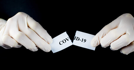 Hands tearing paper with the word Coronavirus. The COVID-19 pandemic is over. Stop the spread and...