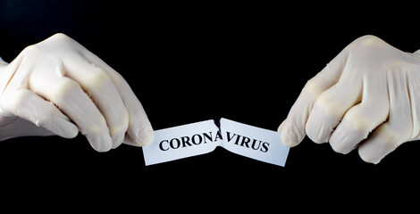Hands tearing paper with the word Coronavirus. The COVID-19 pandemic is over. Stop the spread and...