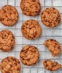 Freshly baked homemade crunchy cookies with chocolate chips, peanut butter or salted caramel. A delicious treat for gourmets. Biscuits on a grey concrete background. Selective focus, top view