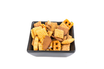 Cereal holiday mix with pretzels and crunchy salty pieces in a bowl isolated over white top down view