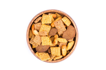 Cereal holiday mix with pretzels and crunchy salty pieces in a bowl isolated over white top down view