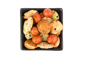 Green red and orange oriental snack mix in a bowl isolated over white  top down view