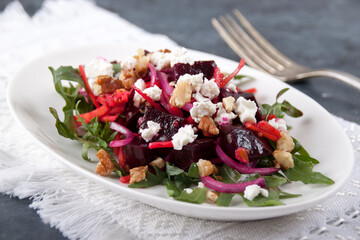 Salad in a white plate on a white napkin on a gray table